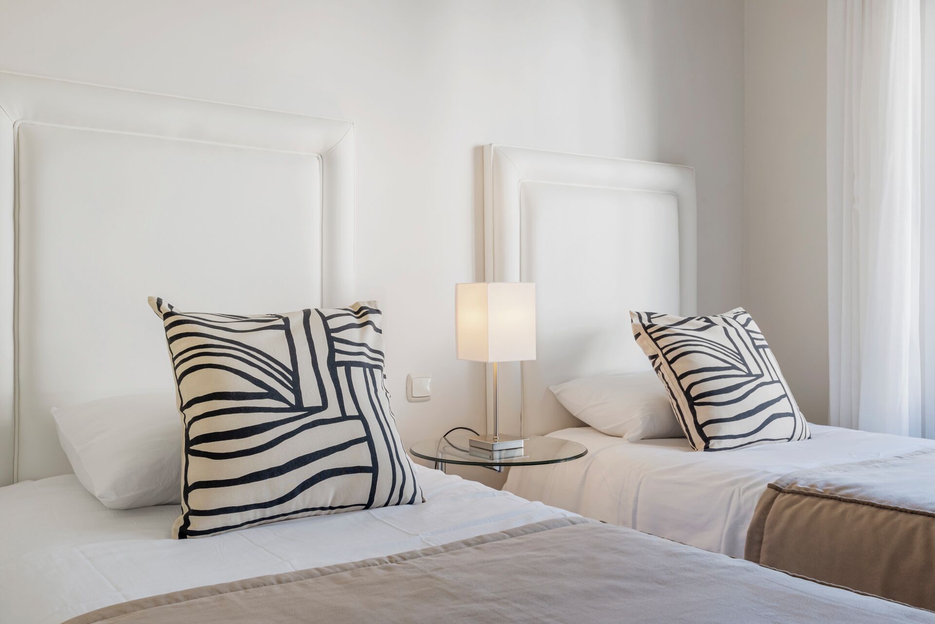 A hotel room with two beds, each with a zebra-patterned pillow and a bedside table with a lamp.