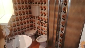 Een badkamer met een wastafel, twee toiletten en een douche.