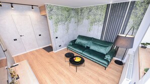 A modern living room with a green sofa, a small round table with fruit, and a floor lamp. - StarDust Apartment - Cismigiu Gardens (Unknown)