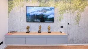 A modern room with a large flat-screen TV mounted on a textured wall, a wooden console table with decorative items, and a door with a handle. - StarDust Apartment - Cismigiu Gardens (Unknown)