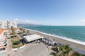 Um hotel à beira-mar, com vista para a praia, área de estar coberta ao ar livre e estacionamento.