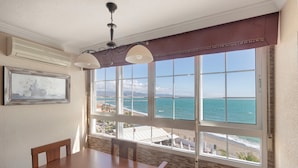 A dining area with a table and chairs, large windows with a view of the ocean, and a ceiling fan. - Beachfront apartment with incredible views of Málaga Bay (Málaga)