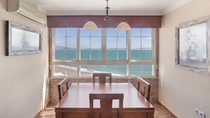 A dining area with a view of the ocean, a ceiling fan, and two wall-mounted lamps. - Beachfront apartment with incredible views of Málaga Bay (Málaga)