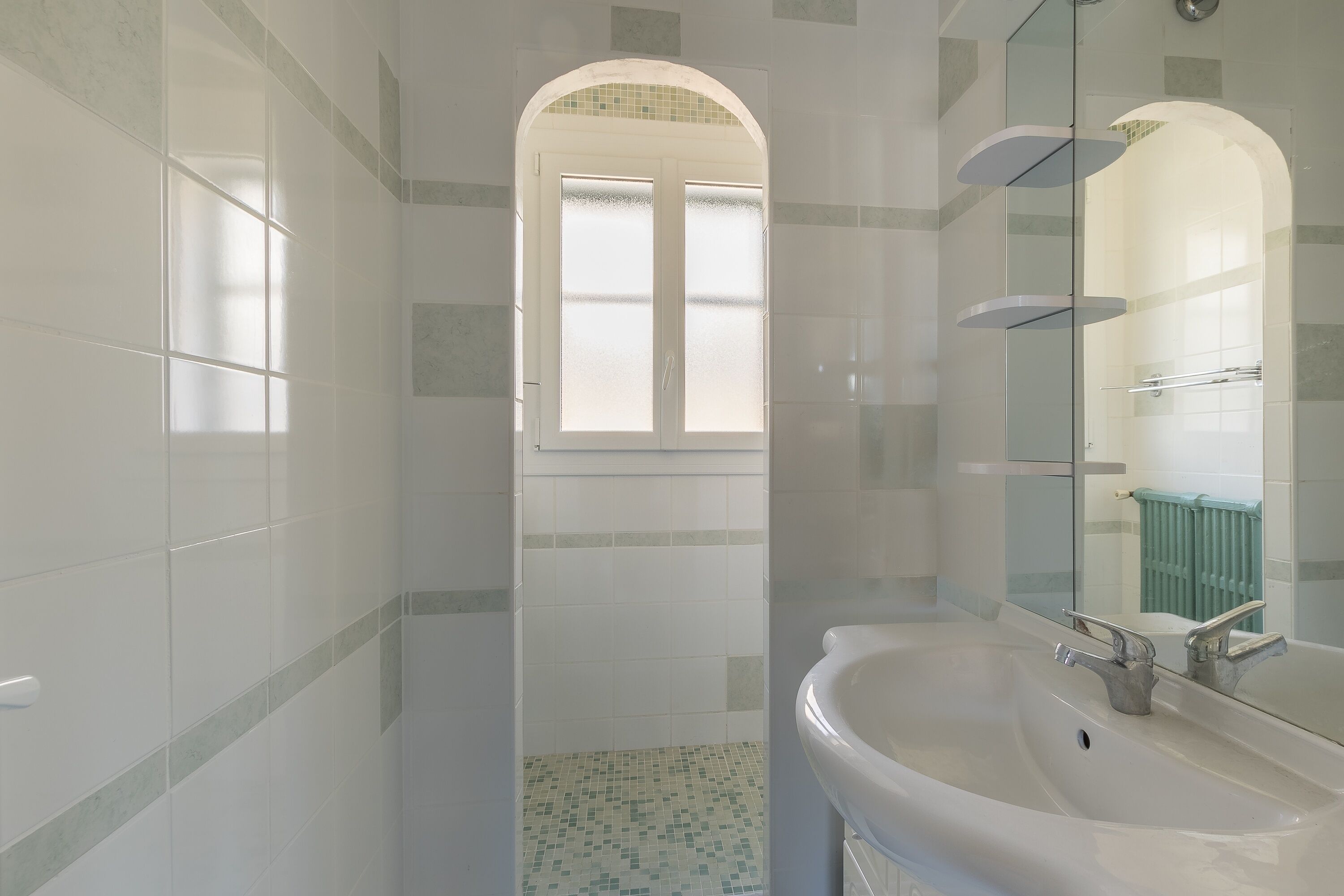 Ein Badezimmer mit einem großen Waschbecken, einem Spiegel und einem Fenster mit Milchglas.