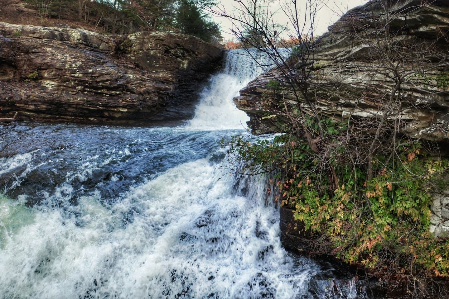 A waterfall cascading over rocky terrain with dense foliage.