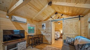 A cozy cabin interior with a TV, seating area, and a bed.