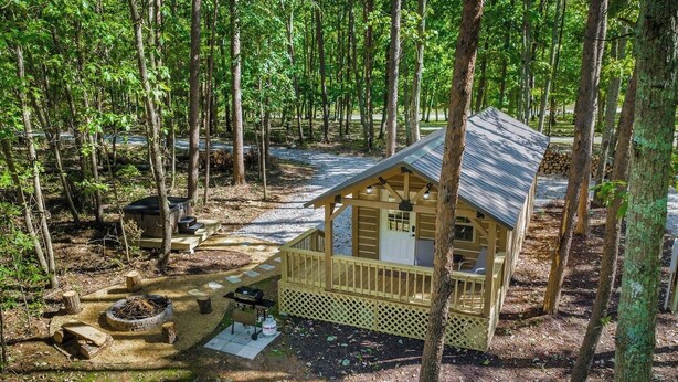 A wooden cabin with a porch, a fire pit, and outdoor seating.