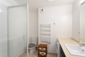 A modern bathroom with a glass shower enclosure, a toilet, a sink, and a mirror. - Cap Vauban - Duplex à 200m de la plage (Saint-Malo)