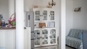 A kitchen with a white cabinet, a refrigerator, and a striped sofa.