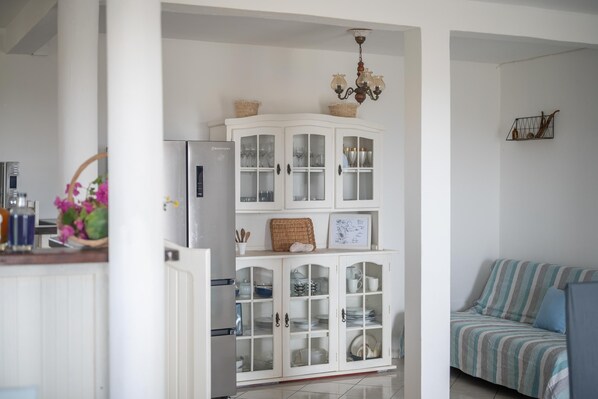 Una cocina con un armario blanco, un refrigerador y un sofá a rayas.