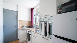 Una cocina compacta equipada con lavadora, microondas y refrigerador.
