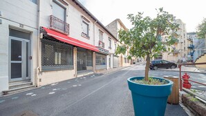 Una calle con edificios, una jardinera azul con un árbol y un hidrante rojo.