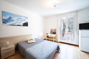 A bedroom with a bed, bedside table, and a painting of a landscape.