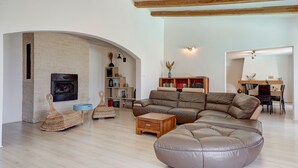 A modern living room with a fireplace, a sectional sofa, and a dining area.