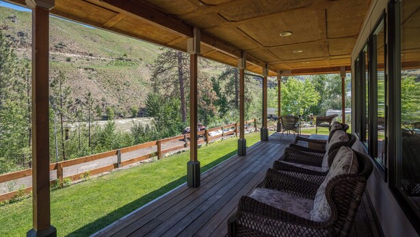 Un espace extérieur aménagé, abrité et doté de mobilier en osier, offrant une vue sur un paysage montagneux.