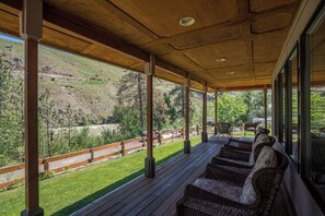 A covered outdoor seating area with wicker furniture and a view of a mountainous landscape. - Charming 2-bedroom house with WiFi, AC in wonderful Pateros (Pateros)