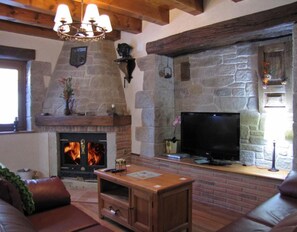 A stone fireplace with a TV on top, a wooden bench, and a leather sofa in a cozy room.