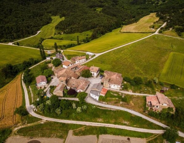 An aerial view of a rural village with traditional houses, winding roads, and surrounding fields.