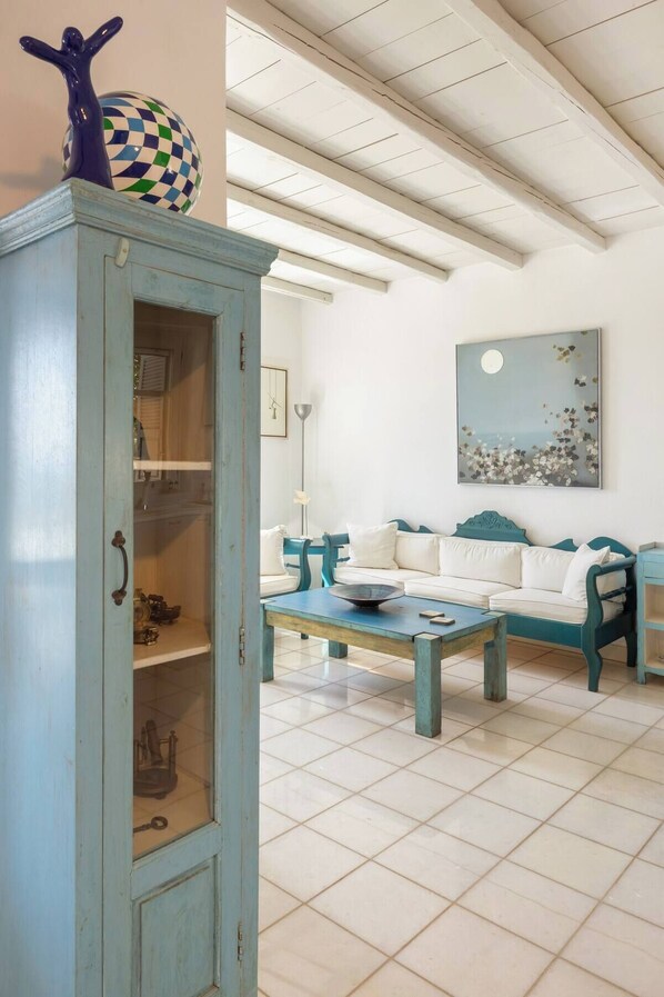 Een woonkamer met een blauwgroene zithoek, een salontafel en een kastje met decoratieve objecten.
