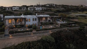 A hillside residential area with white houses, a well-maintained garden, and a paved pathway. - Isterni | 3BR House with Sea View & BBQ | Blue Coral 2 (Paros)