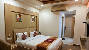 A hotel room with a wooden bed, a desk, and a chair. - Capital Plaza Residency (Mannarkkad)