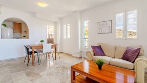 A modern living room with a sofa, coffee table, and dining area with chairs. - Apartment 'El Mirador' with Sea View, Wi-Fi and Air Conditioning (Mutxamel)