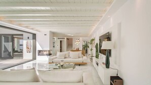 A modern living room with a white sofa, glass coffee table, and a large mirror.
