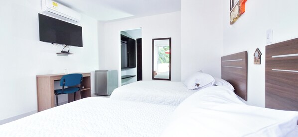 A hotel room with a bed, a desk with a chair, a television, and a wardrobe.