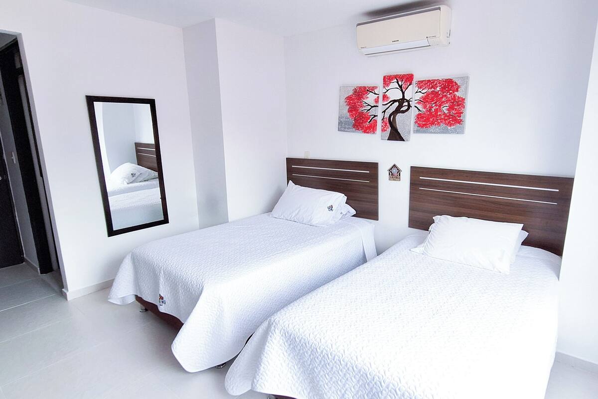 Ein Hotelzimmer mit zwei Betten, einem großen Spiegel und einer Wandklimaanlage.