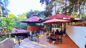 An outdoor patio with wooden flooring, red umbrellas, and wooden tables and chairs. - HOTEL SUMAWASI (Mocoa)