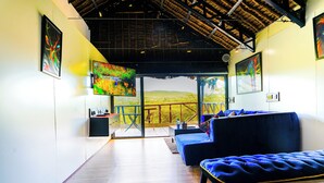 A modern interior with a wooden floor, a blue sofa, and a large TV screen. - Kitumo Mara Lodges  (Maasai Mara)