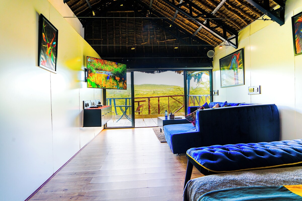 A modern interior with a wooden floor, a blue sofa, and a large TV screen.