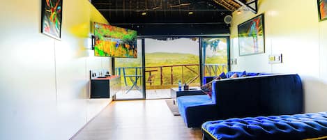 A modern interior with a wooden floor, a blue sofa, and a large TV screen.