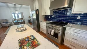 Una cocina moderna con armarios blancos, estufa de acero inoxidable y salpicadero de azulejos azules.