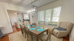 Un comedor con una mesa de madera, individuales azules y seis sillas.