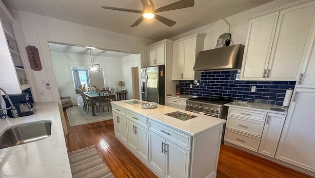 Una cocina moderna con armarios blancos, una isla central, una estufa y un ventilador de techo.