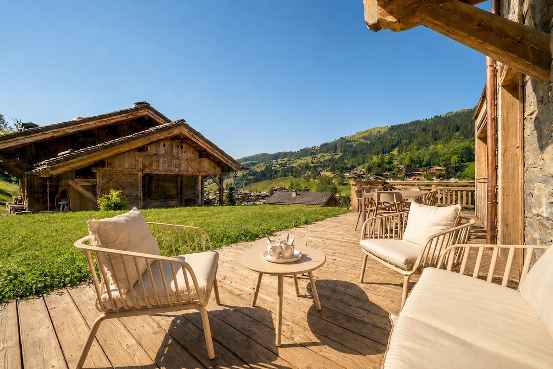 Eine Holzterrasse mit Sitzgelegenheiten im Freien, ein rustikales Gebäude und Blick auf ein grünes Tal.