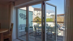 Un balcon avec une porte vitrée, un canapé en osier, une table à manger et des chaises.