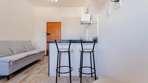 Una cocina compacta con una puerta de madera, un taburete de bar y un horno empotrado.
