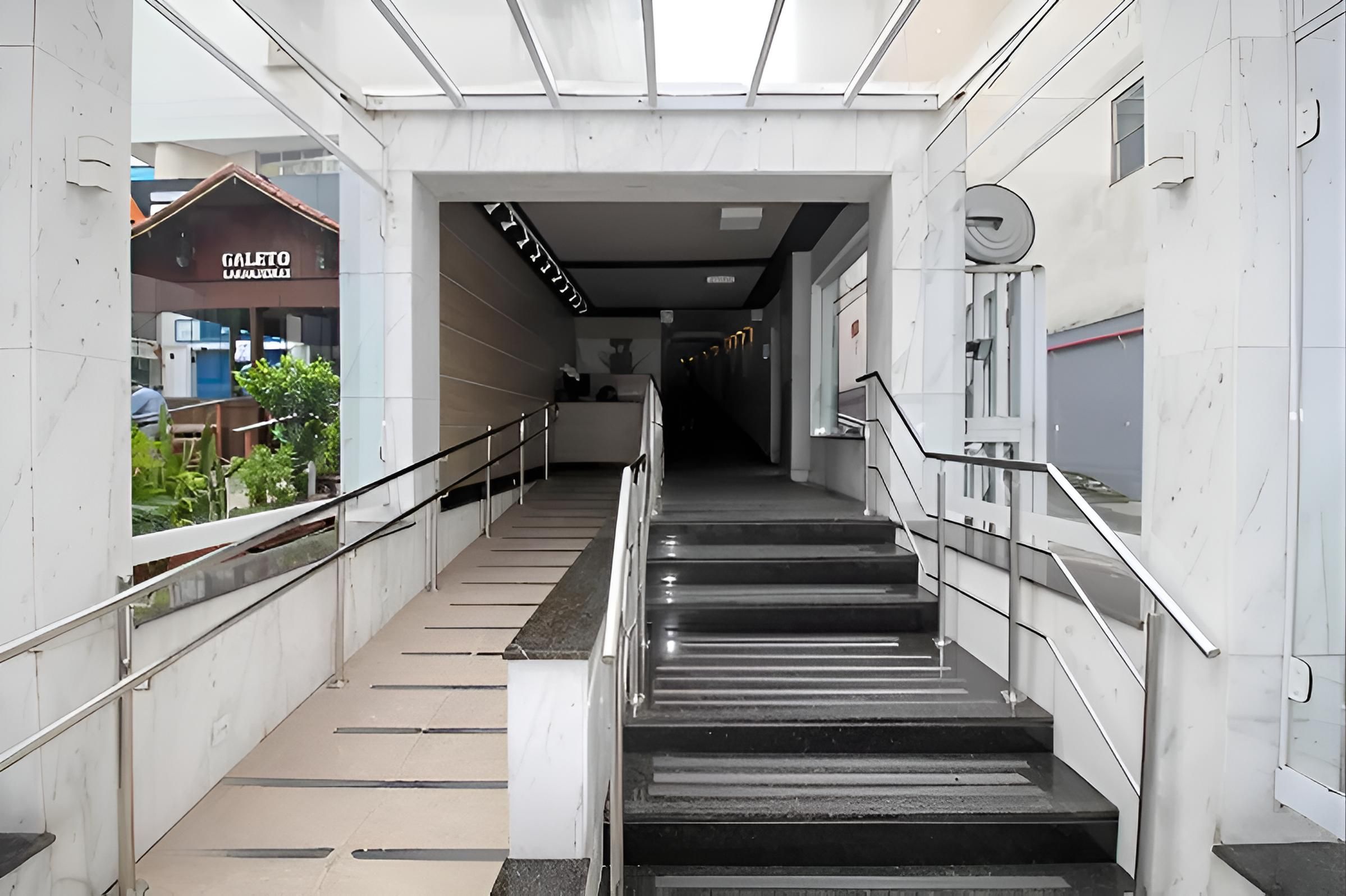 A modern indoor staircase with metal railings and a glass ceiling.
