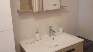 Een badkamer met een witte wasbak, een spiegel, een handdoekhouder en een douchegordijn.