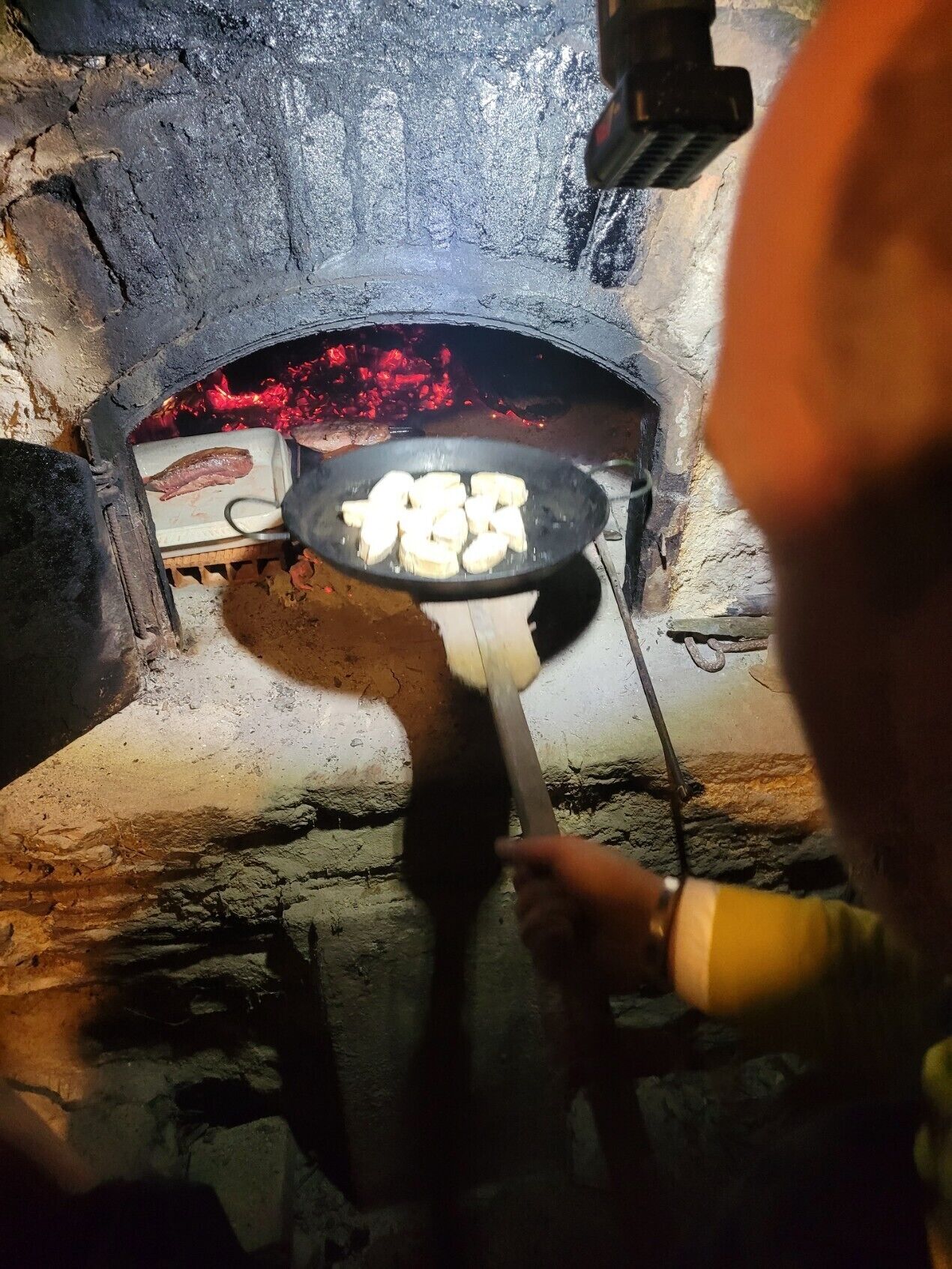 A person cooking food in a traditional stone oven.