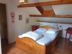 Une chambre à coucher avec un lit en bois, un plafond en pente et une table de chevet rouge.