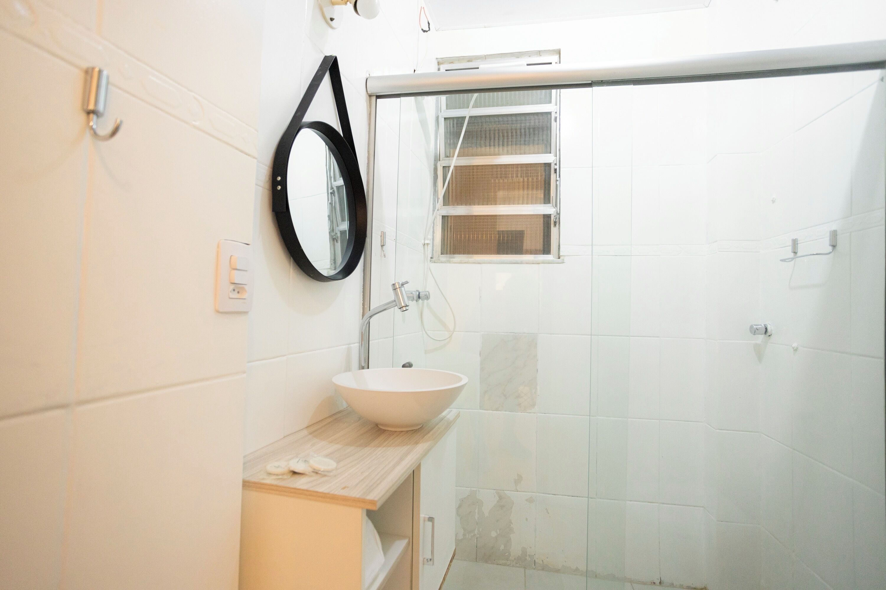 Un baño con lavamanos blanco, un espejo y una cabina de ducha.