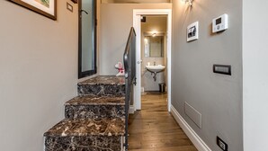A hallway with marble steps, a door leading to a bathroom, and wall-mounted light fixtures. - Room 'Pretty Suite Firenze' with Private Garden, Wi-Fi and Air Conditioning (Fiesole)