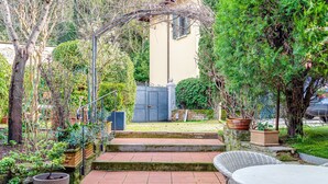 A garden with steps leading to a patio area, a white wicker table, and a potted plant. - Room 'Pretty Suite Firenze' with Private Garden, Wi-Fi and Air Conditioning (Fiesole)