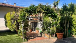 A courtyard with a brick pathway leading to a building entrance, surrounded by lush greenery and potted plants. - Room 'Pretty Suite Firenze' with Private Garden, Wi-Fi and Air Conditioning (Fiesole)