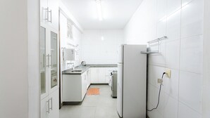 A modern kitchen with white cabinets, a refrigerator, and a countertop. - SUH Catete 06 Big House Metro (Rio de Janeiro)