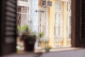 Una ventana con reja de metal, una planta en maceta y un balcón con barandilla.