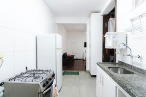 A compact kitchen with a gas stove, a refrigerator, and a sink. - SUH Catete 06 Big House Metro (Rio de Janeiro)